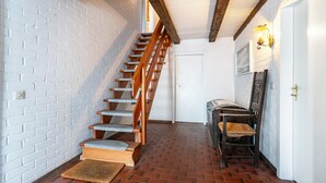 A staircase with wooden steps and a white brick wall. - Apartment Nolde, 33 sqm, 1 Bedroom, Max. 2 Guests (Pellworm)