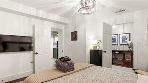 Un dormitorio con cama, televisión, puerta y armario.