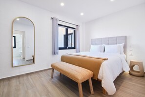 A modern bedroom with a large bed, a bench, a mirror, and a window with curtains. - Finca El Moral by Huskalia - Apartamento 1 (Los Llanos de Aridane)