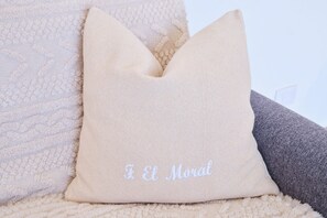 A beige pillow with embroidered text, placed on a textured surface. - Finca El Moral by Huskalia - Apartamento 1 (Los Llanos de Aridane)