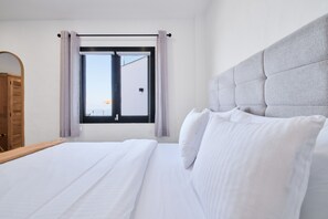 Une chambre d’hôtel avec un grand lit, une tête de lit, une fenêtre avec des rideaux et une armoire en bois.