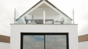 Un bâtiment moderne doté d’un balcon en verre et d’une grande fenêtre.