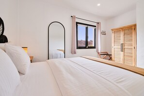Ein Schlafzimmer mit einem Bett, einem großen Spiegel, einem Fenster mit Blick und einem Kleiderschrank.