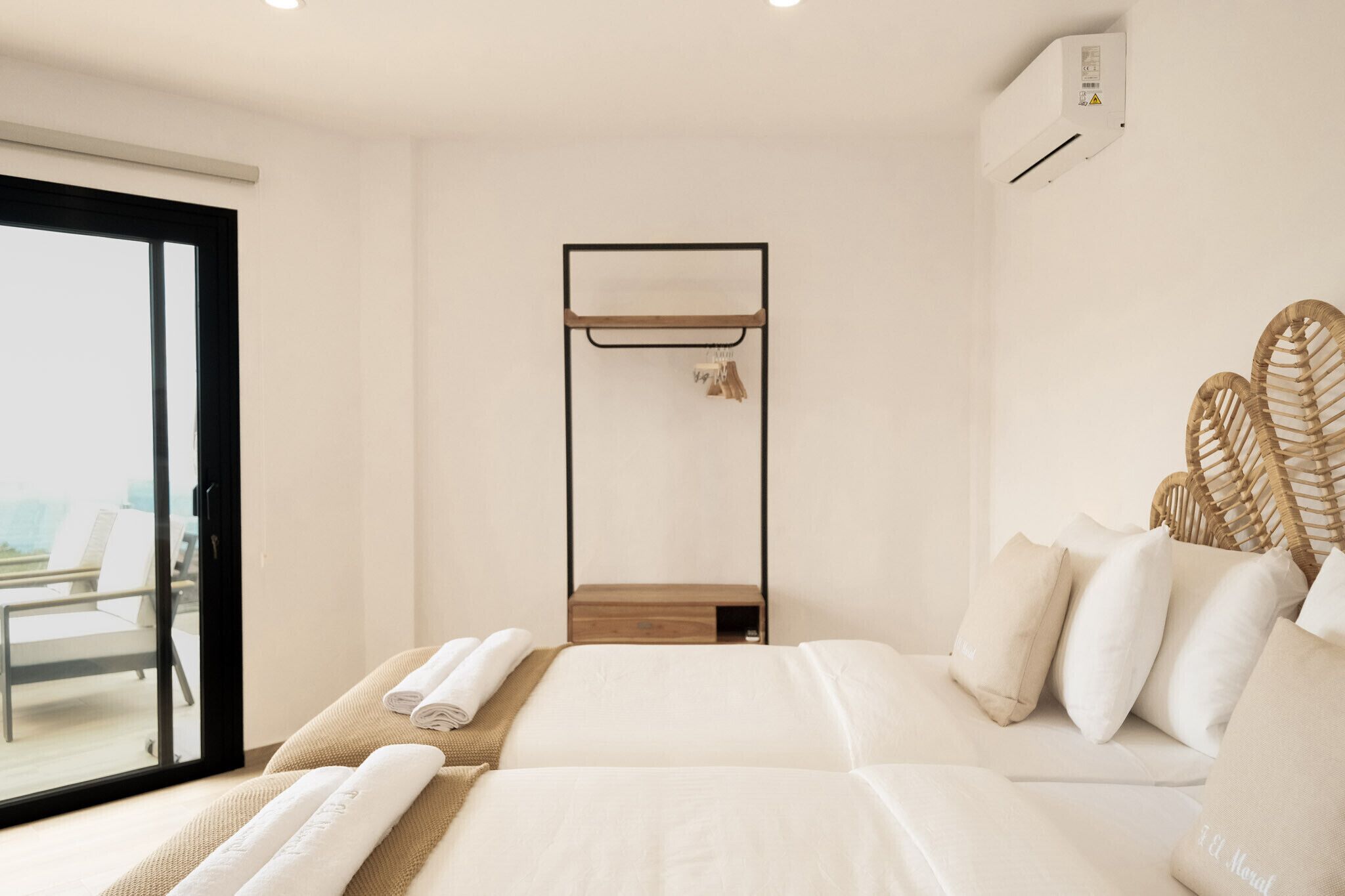 A modern hotel room with a large bed, a built-in wardrobe, and a balcony with a view.