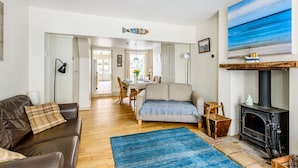 A living room with a sofa, a rug, a fireplace, and a dining area in the background. - Rose Cottage - sleeps 4 guests  in 2 bedrooms (Burnham Market)