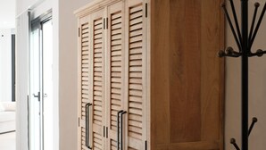 Un armario de madera con puerta corredera y un perchero con ganchos.