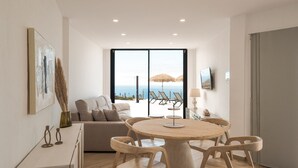 Una sala de estar moderna con una mesa redonda de madera y sillas, un sofá y un ventanal con vistas al mar.