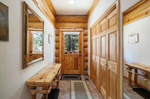 A log cabin interior with a wooden bench, a door leading outside, and a mirror on the wall. - Mashie Meadows log home hot tub boot dryer sleeps 10 + 2 close to skiing & beach (Tahoe Vista)