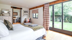 Un dormitorio con una cama grande, un escritorio, una silla y un ventanal con cortinas.