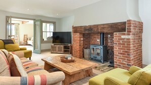 Una sala de estar con chimenea de ladrillo, sofás, una televisión y una mesa de centro de madera.