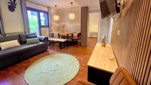 Un salon moderne avec un canapé, une table à manger et un téléviseur fixé au mur.