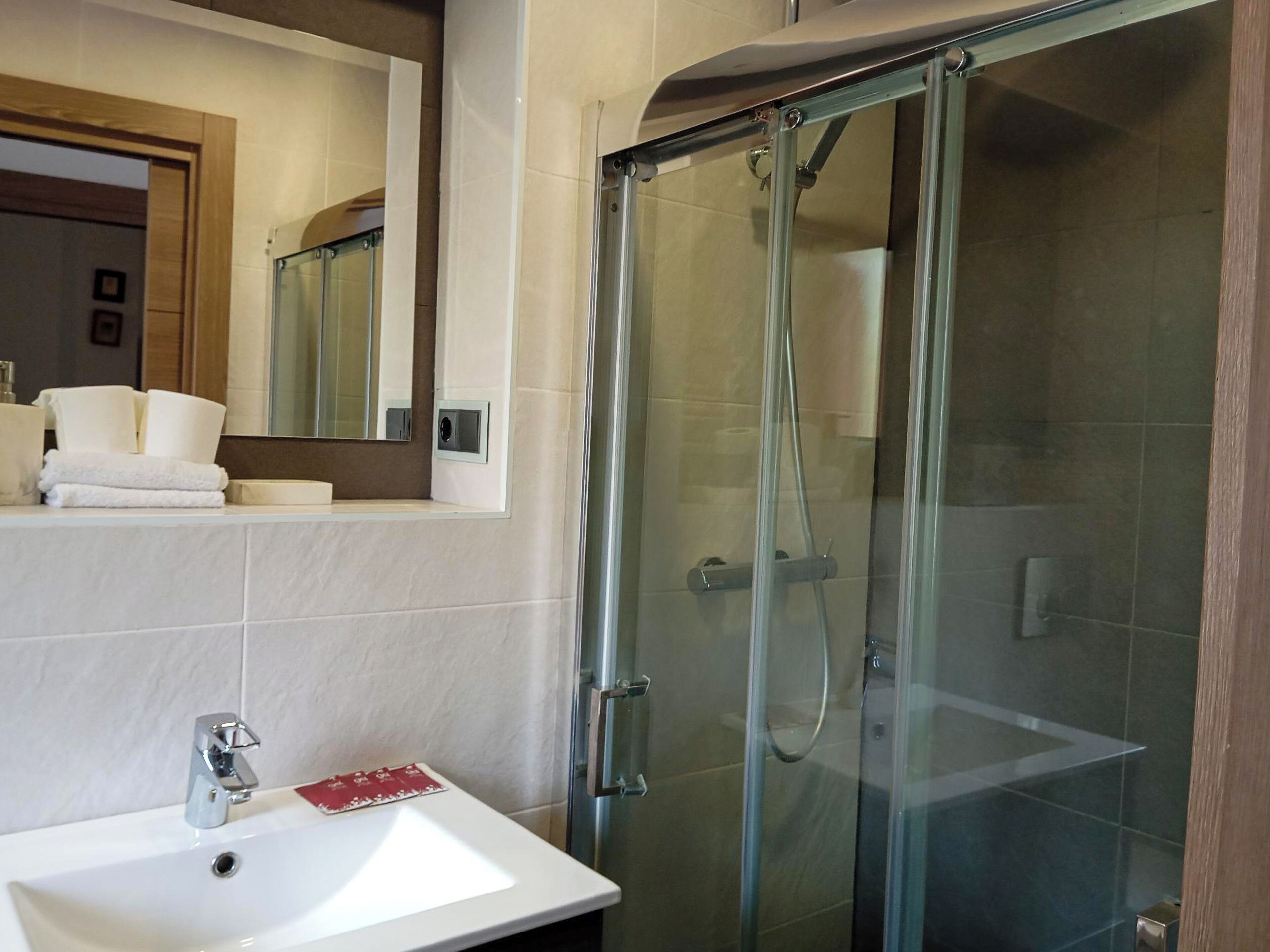 A modern bathroom with a glass-enclosed shower, a white sink, and a mirror above the sink.