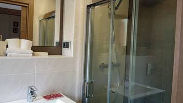 A modern bathroom with a glass-enclosed shower, a white sink, and a mirror above the sink.