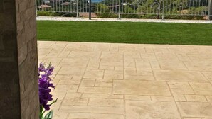 A patio with a stone floor, a view of the ocean, and a fence with greenery behind it. - RIVIELLO ROOMS. (Marina di Camerota)