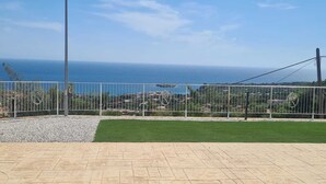 A paved patio area with a view of the sea and a fenced garden. - RIVIELLO ROOMS. (Marina di Camerota)