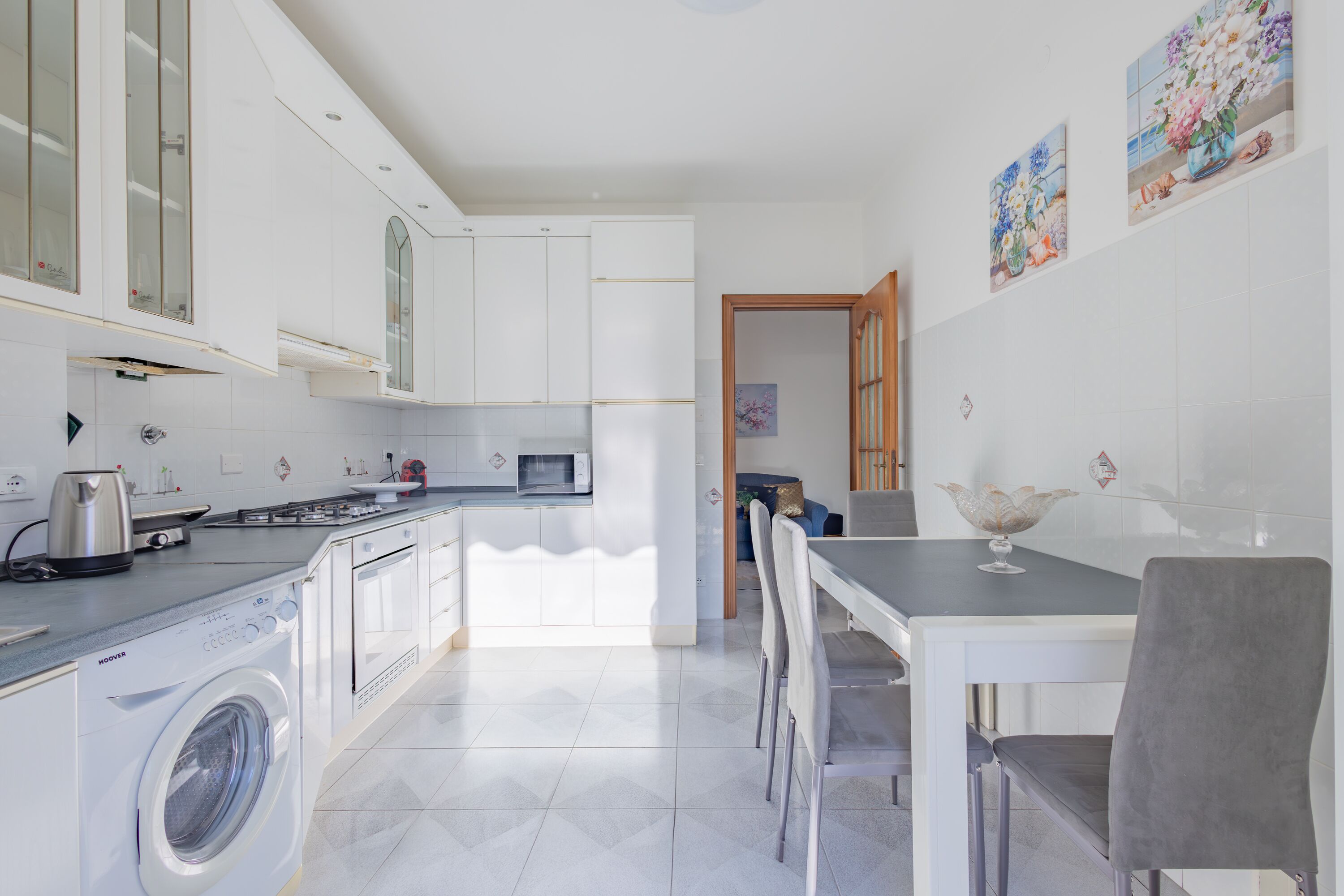 A modern kitchen with a built-in washer, a dining area with a table and chairs, and a view of the adjacent room.
