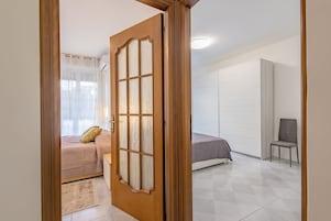 Un dormitorio con cama, una silla y un armario.
