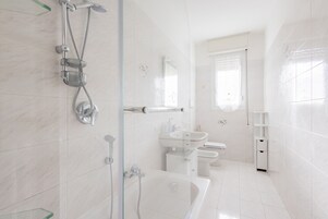 Un baño moderno con ducha de vidrio, lavamanos blanco y retrete.