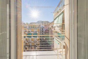 Un balcón con vistas a un paisaje urbano, con edificios que también tienen balcones y un cielo despejado.