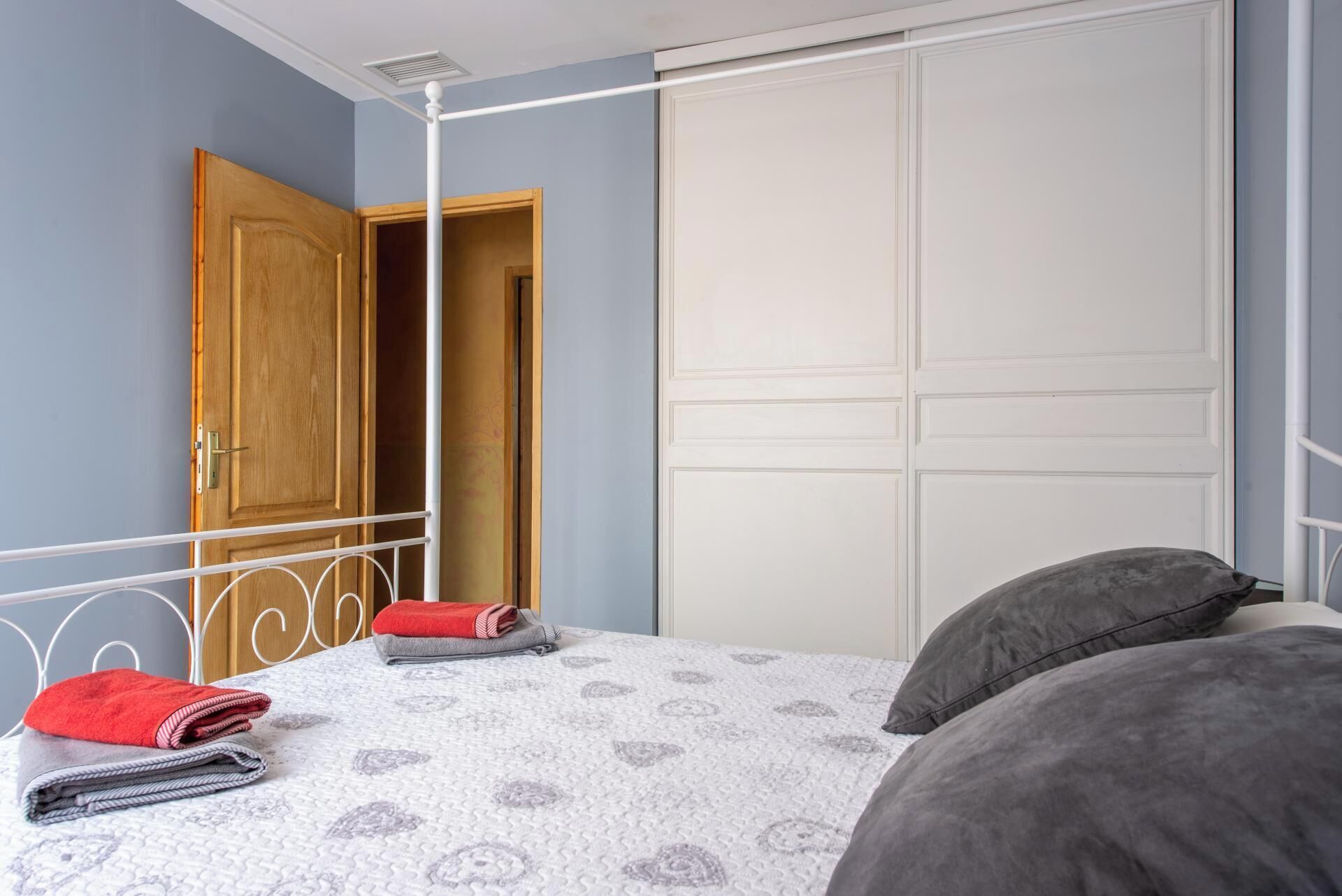 A bedroom with a bed, a wardrobe, and a door.