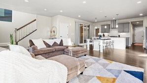 En moderne stue med sofa, spiseplads og køkken.