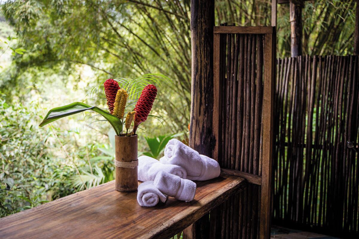 A wooden bench with rolled towels and a vase with plants.
