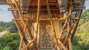 Une structure en bambou avec une passerelle en bois menant à une plateforme d’observation circulaire.