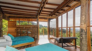Une cabane équipée de deux lits, d’un banc et de grandes fenêtres donnant sur le paysage extérieur.
