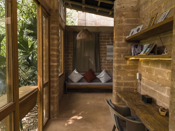 A cozy room with a wooden bench, a hanging light fixture, and a brick wall with shelves.