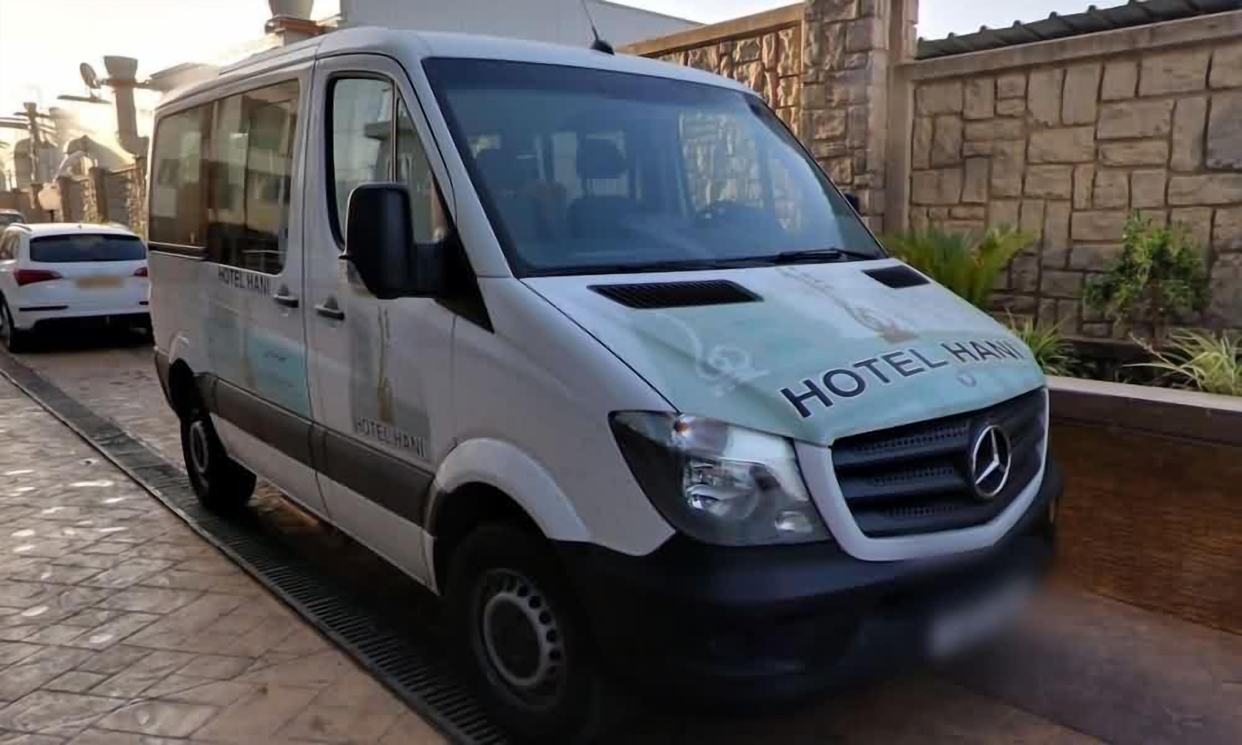 A white van with "HOTEL HAMIL" branding, parked on a paved street.
