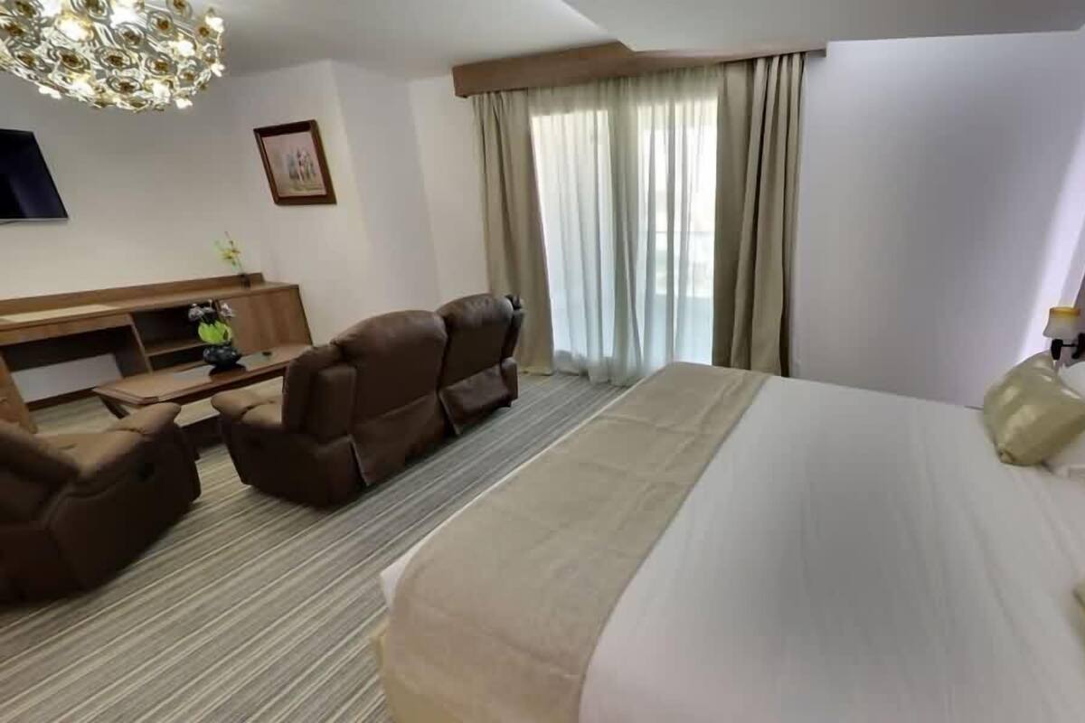 Una habitación de hotel con una cama grande, un escritorio con una silla, un sofá y un televisor en la pared.