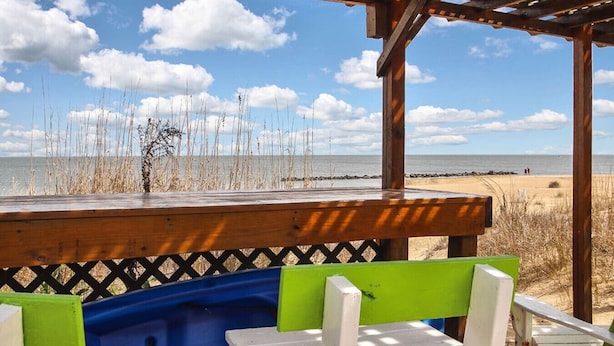 Un espace aménagé avec des sièges, situé au bord de la plage, doté d’une terrasse en bois et offrant une vue sur l’océan.