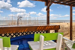 Un espace aménagé avec des sièges, situé au bord de la plage, doté d’une terrasse en bois et offrant une vue sur l’océan.