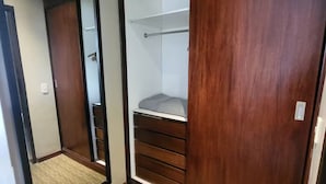 Una cabina armadio con un armadio a specchio, un'asta appendiabiti e una mensola integrata.