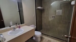 Un bagno moderno con un ampio specchio, un lavabo, un WC e una doccia con pareti in vetro.