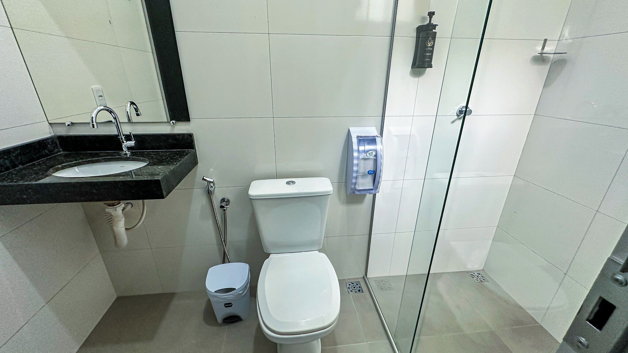 A modern bathroom with a toilet, bidet, and a glass shower enclosure.