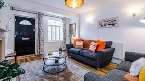 Een moderne woonkamer met een grijze bank, een salontafel en een zwarte deur.