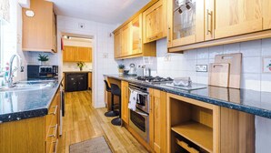 Een moderne keuken met houten kastjes, een zwart aanrecht en roestvrijstalen apparatuur.