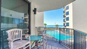 Ein Balkon mit Blick auf einen Swimmingpool und ein Gebäude gegenüber dem Wasser.