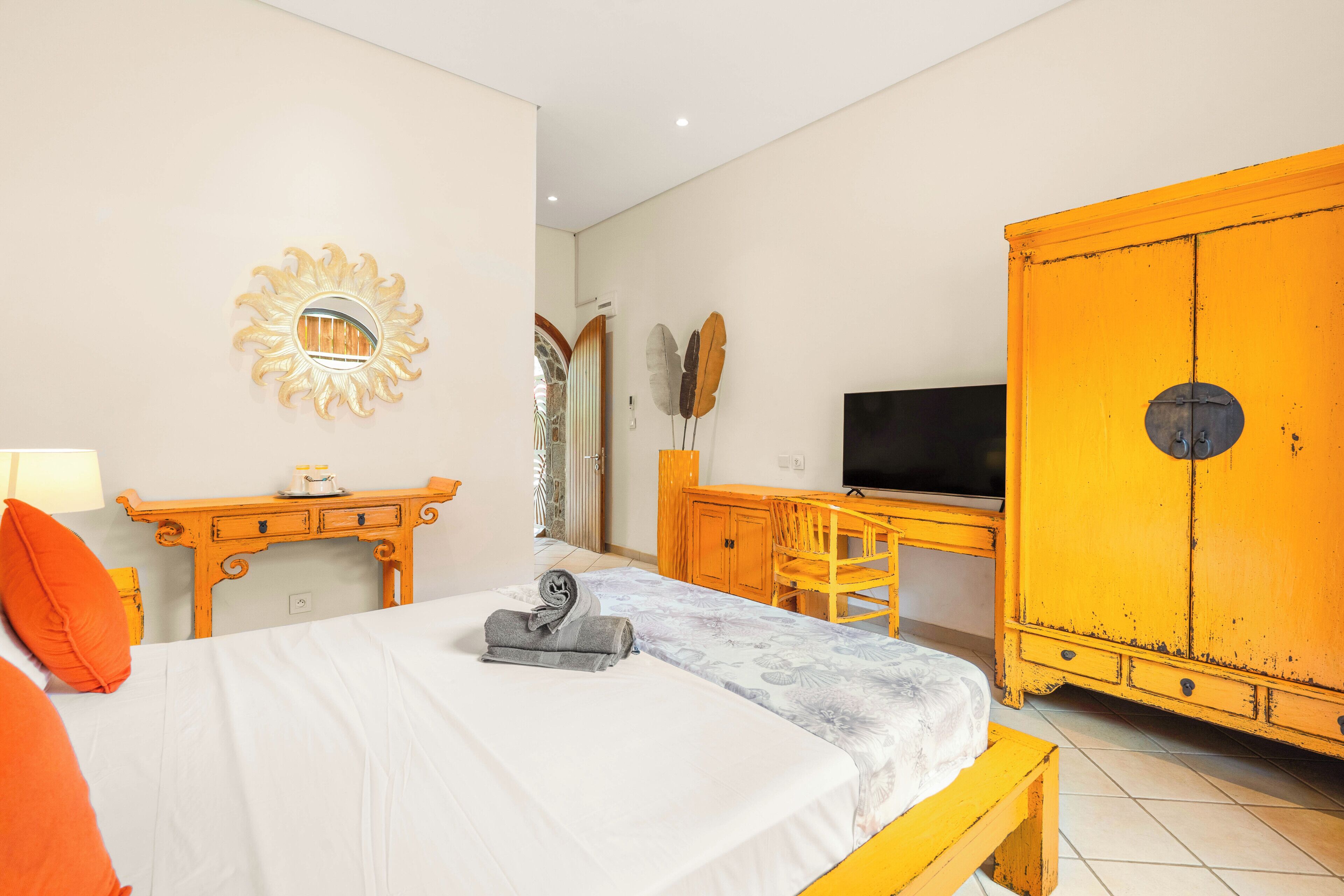 Une chambre à coucher avec un lit, un bureau, une télévision et une armoire.