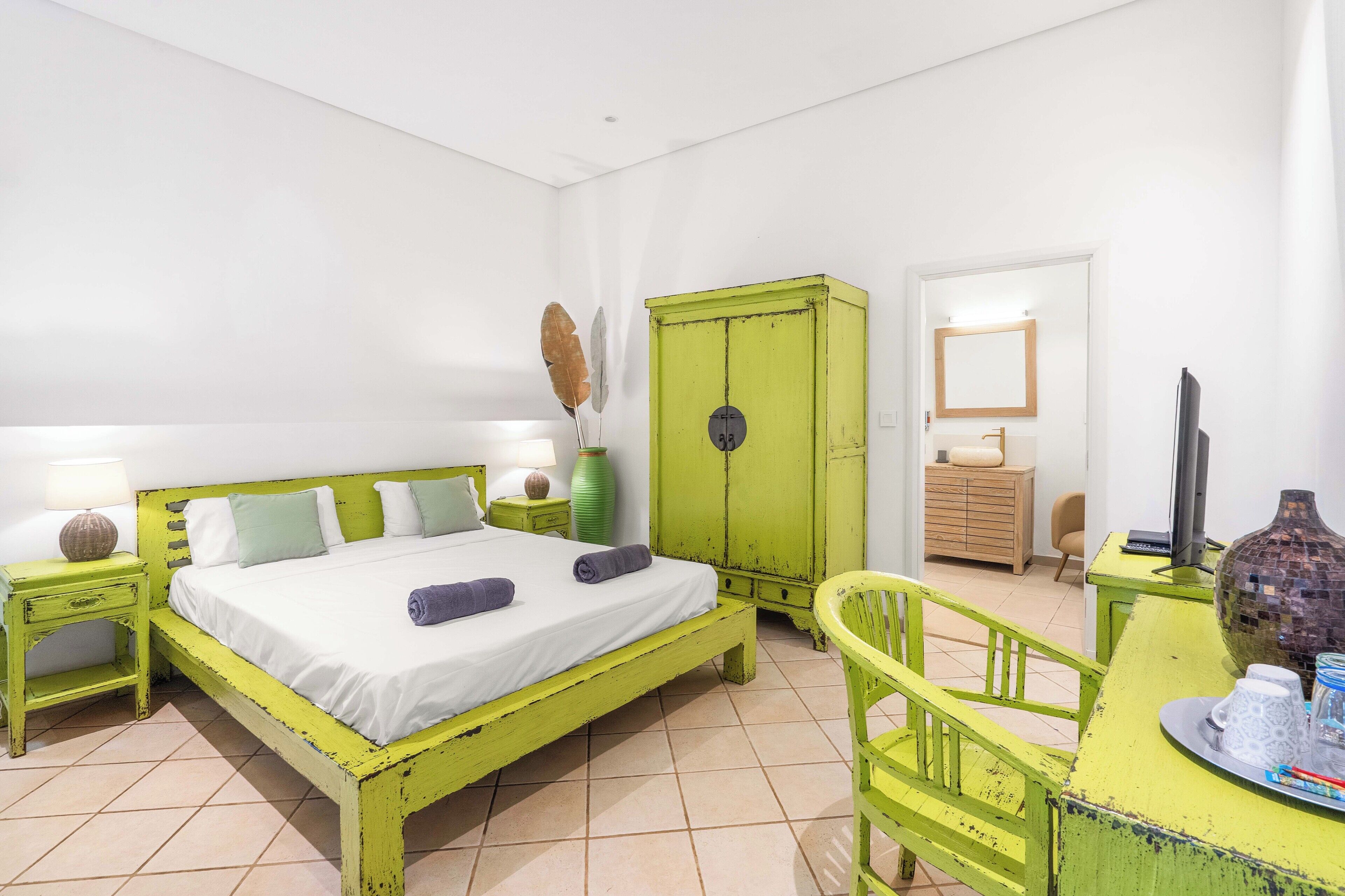Een kamer met een bed, een bureau, een stoel, een kledingkast en een spiegel.