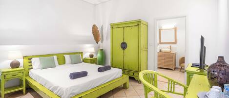 Een kamer met een bed, een bureau, een stoel, een kledingkast en een spiegel.