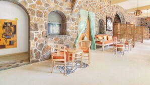 A stone-walled room with a fireplace, wooden furniture, and a patterned rug. - Aroma Plaza Boutique Hotel (Cap Malheureux)