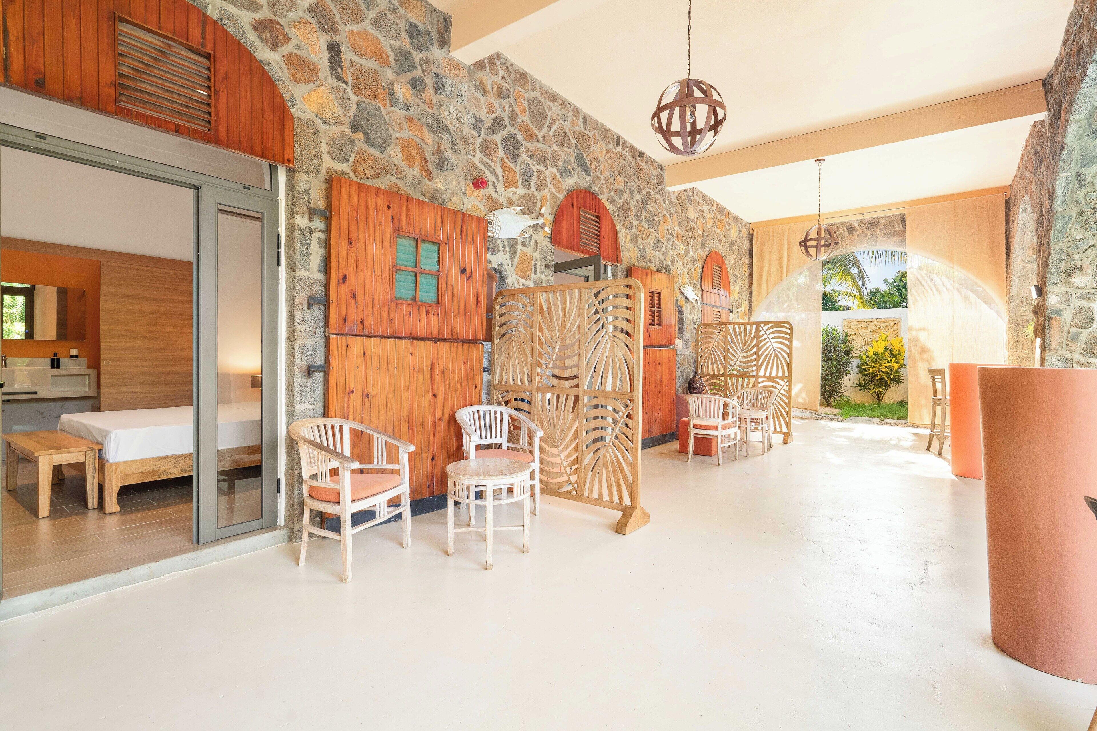 A modern interior with stone walls, wooden furniture, and a view of greenery.