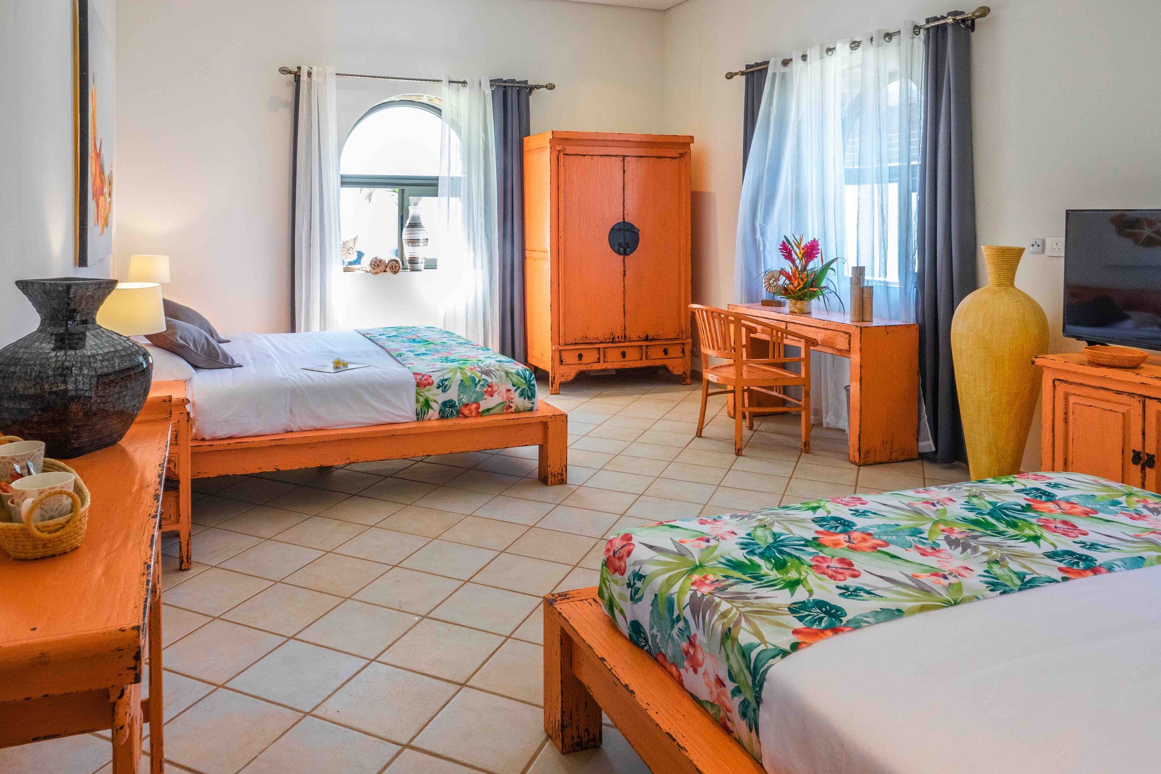 A hotel room with two beds, a desk, a television, and a wardrobe.