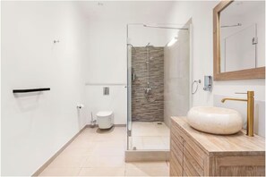 A modern bathroom with a glass shower enclosure, a white toilet, and a marble sink with a gold faucet. - Aroma Plaza Boutique Hotel (Cap Malheureux)