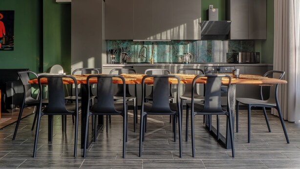 A modern kitchen with a dining area, featuring a large table with chairs, a stove, and a microwave. - Niabi 4BDR Apartments with billiards  (Tbilisi)