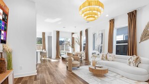 Un salon moderne avec un canapé blanc, une table basse ronde et une grande fenêtre avec des rideaux.