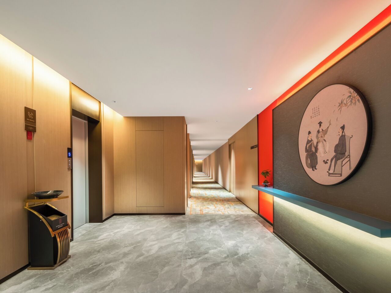 A modern hotel corridor with a marble floor, wooden walls, and a reception area with a traditional artwork.