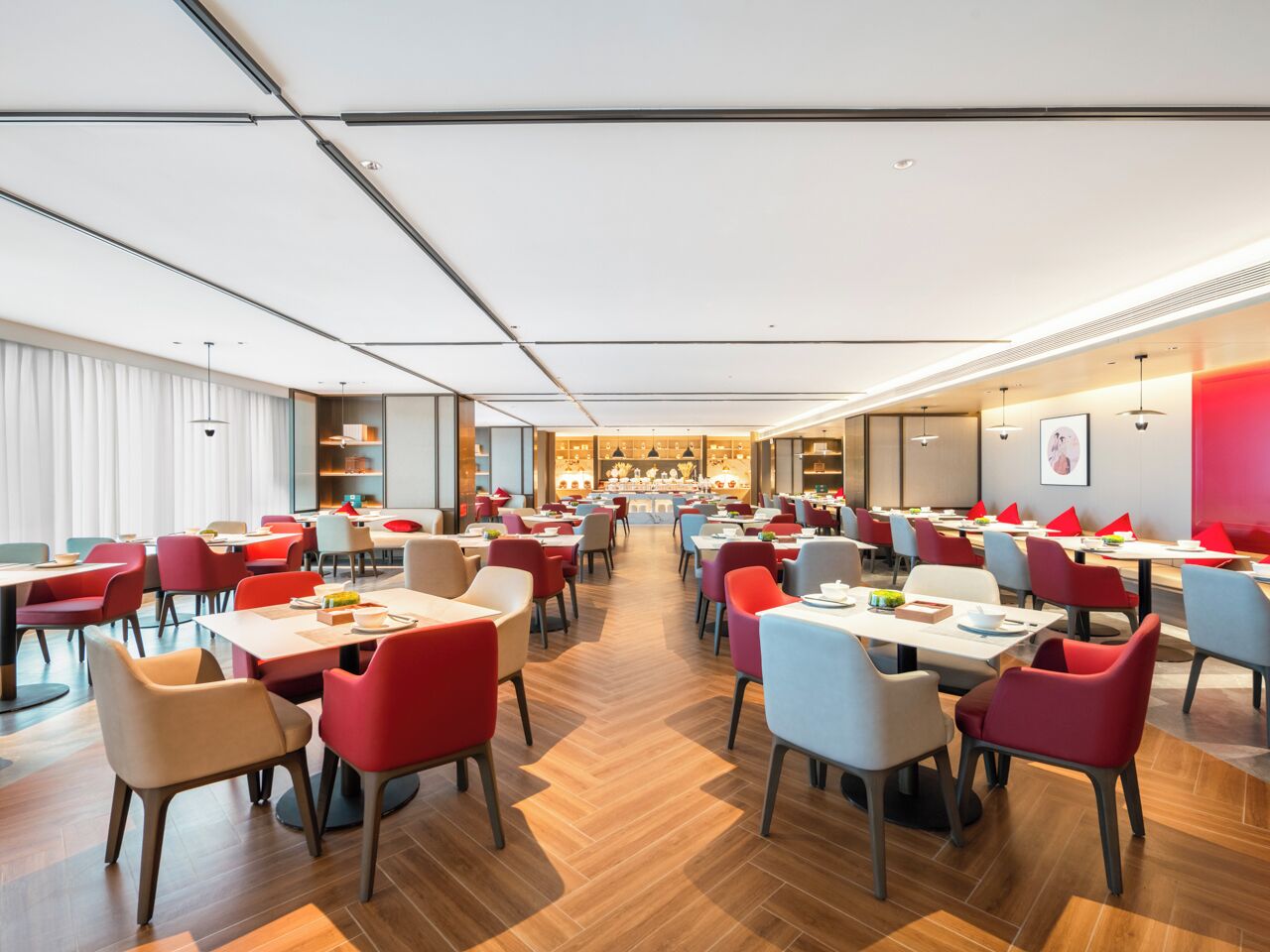 A spacious restaurant with multiple tables and chairs, a central dining area, and a modern ceiling design.